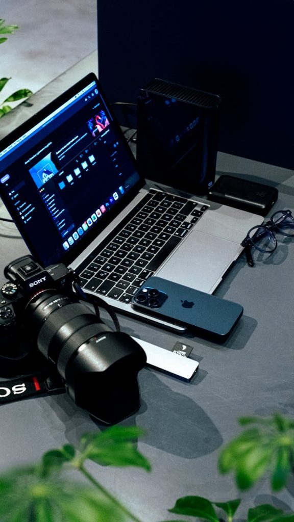 pexels-photo-29824592 A creative workspace featuring a laptop, camera, and smartphone, ideal for photographers and videographers.