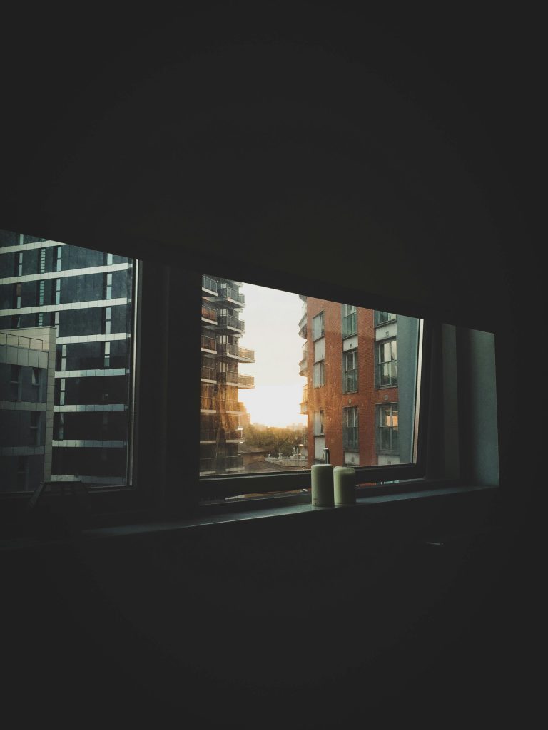 pexels-photo-1717087-1717087 Moody cityscape view through window at sunset, highlighting modern urban living.