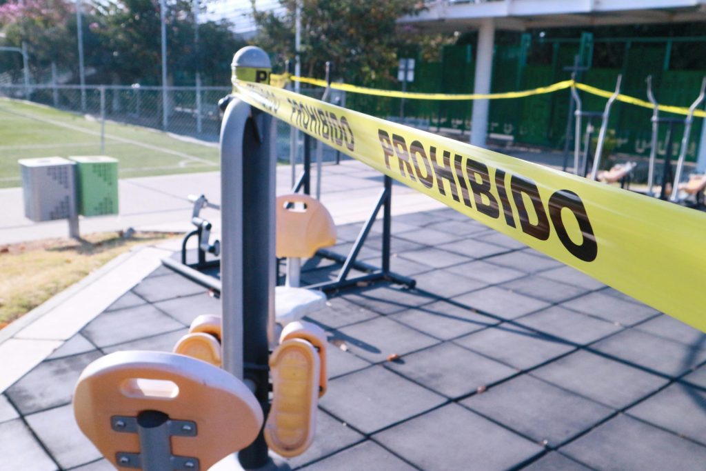 Yellow caution tape blocks access to outdoor gym equipment in Oaxaca, Mexico.