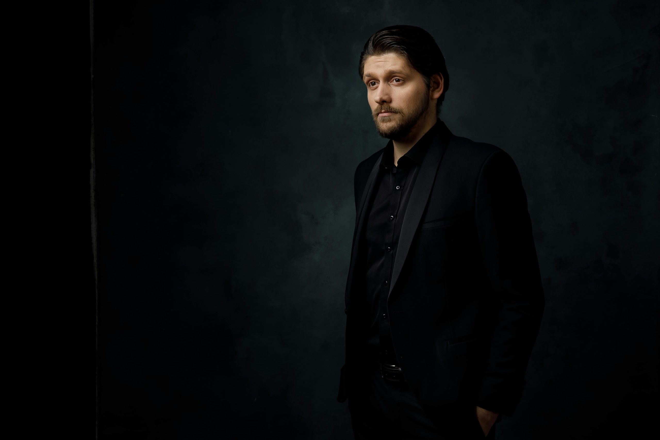 Stylish portrait of a man in black suit on a dark background, showcasing elegance and sophistication.